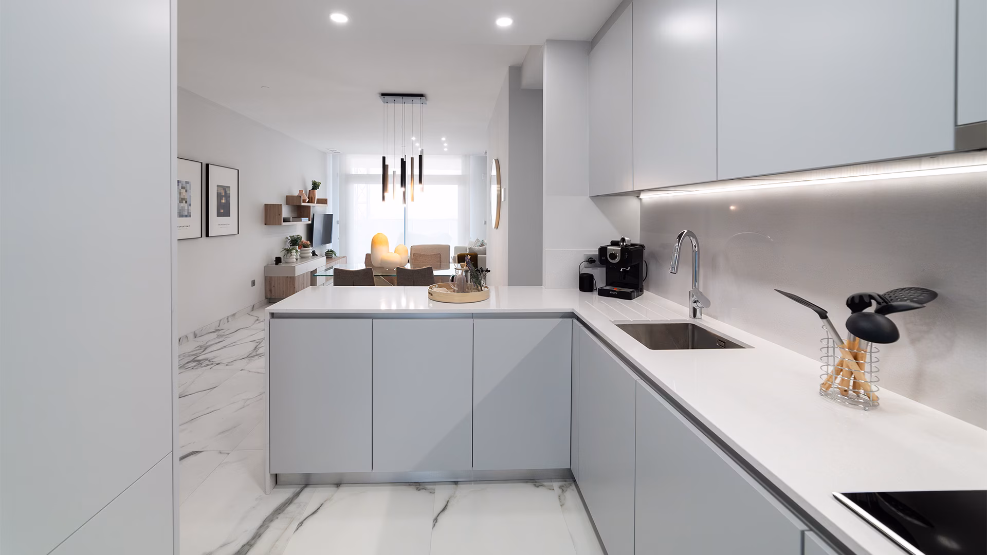L-shaped kitchen with white worktop and marble-effect floor