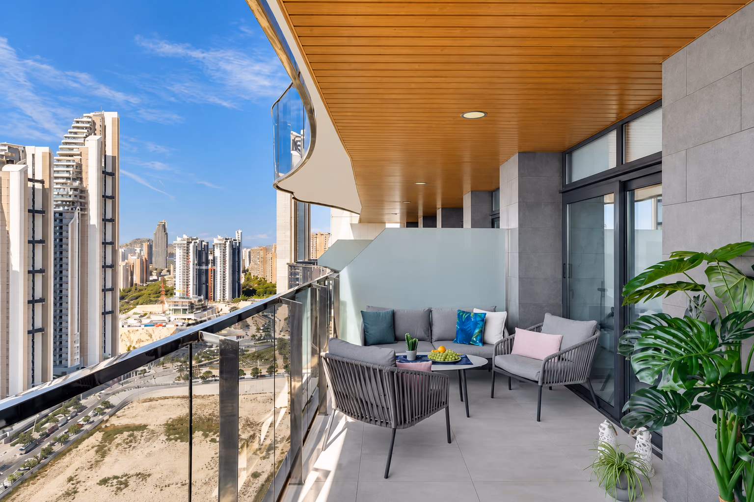 Sitzecke auf der Terrasse am Glasgeländer, unten Türme und Strand