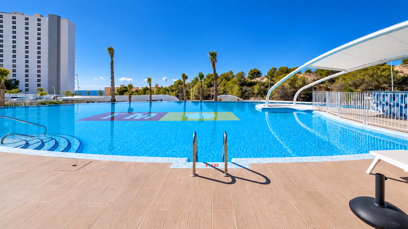 Großer Außenpool mit Sonnendeck, Palmen und einem Sonnensegel