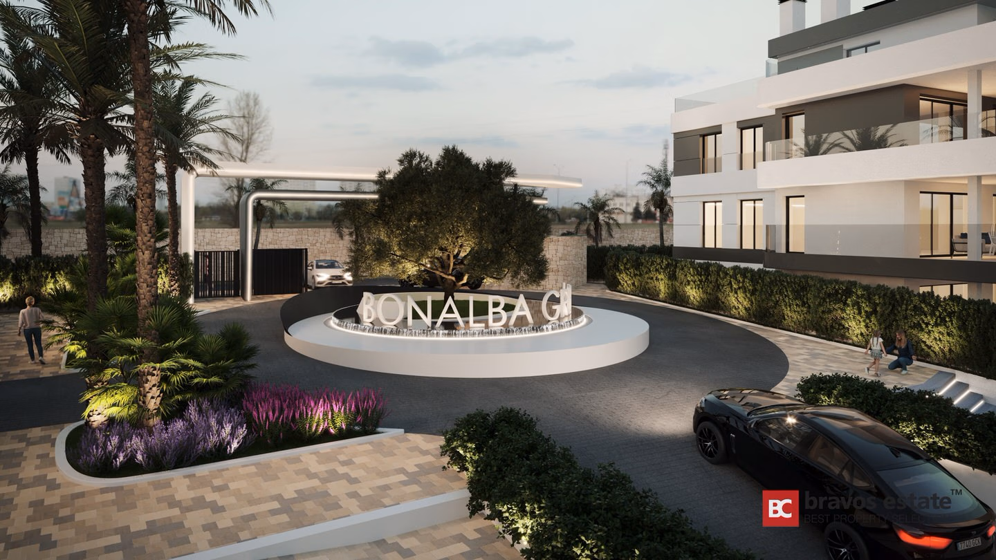 Render CGI de la rotonda de entrada iluminada de Bonalba Green con monumento identificativo, acceso con verja, palmeras y el edificio de apartamentos blanco moderno al atardecer.