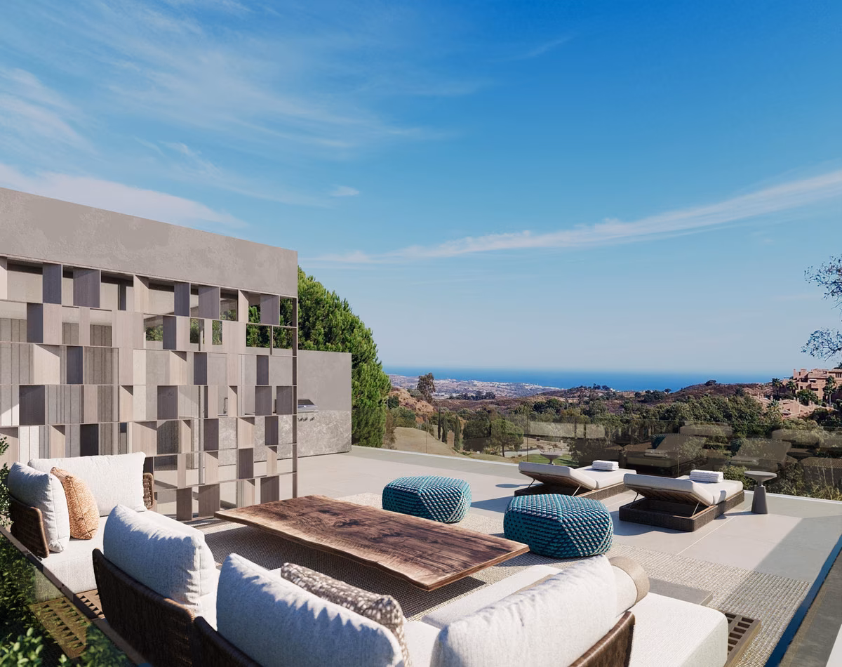 Terrassenlounge mit Sofas und Blick über grüne Hügel aufs Meer