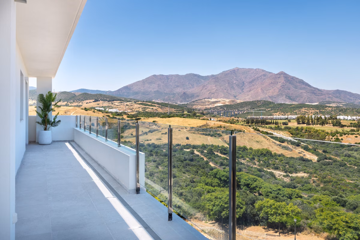 Upper-floor terrace with glass balustrade facing the Sierra Bermeja