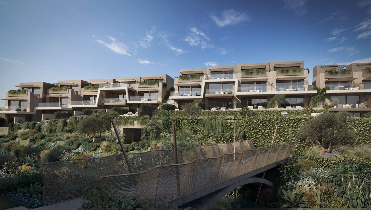 Rows of townhouses above a planted gully with a timber footbridge, The Valley, Elviria