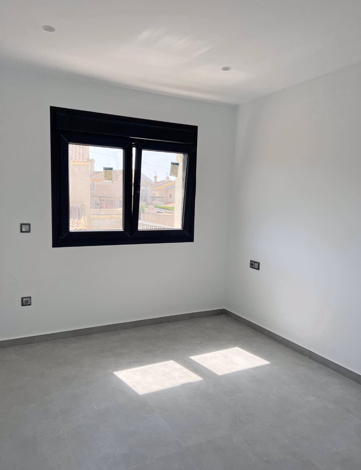 Bedroom with black-framed window and grey porcelain floor