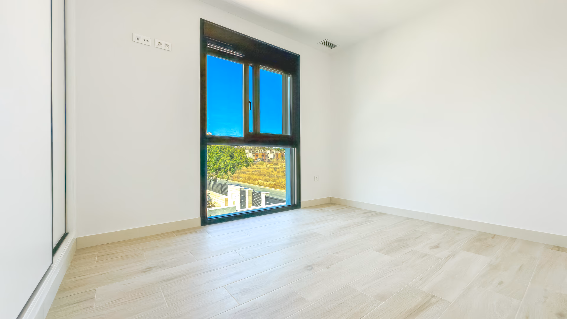 Schlafzimmer mit großem Panoramafenster und Blick ins Grüne