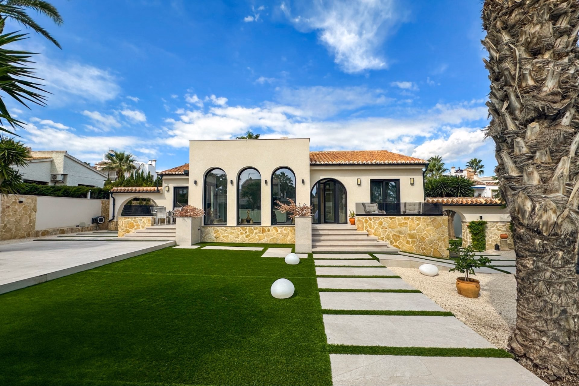 Front of the refurbished villa in Villamartín with arched windows and a lawned garden