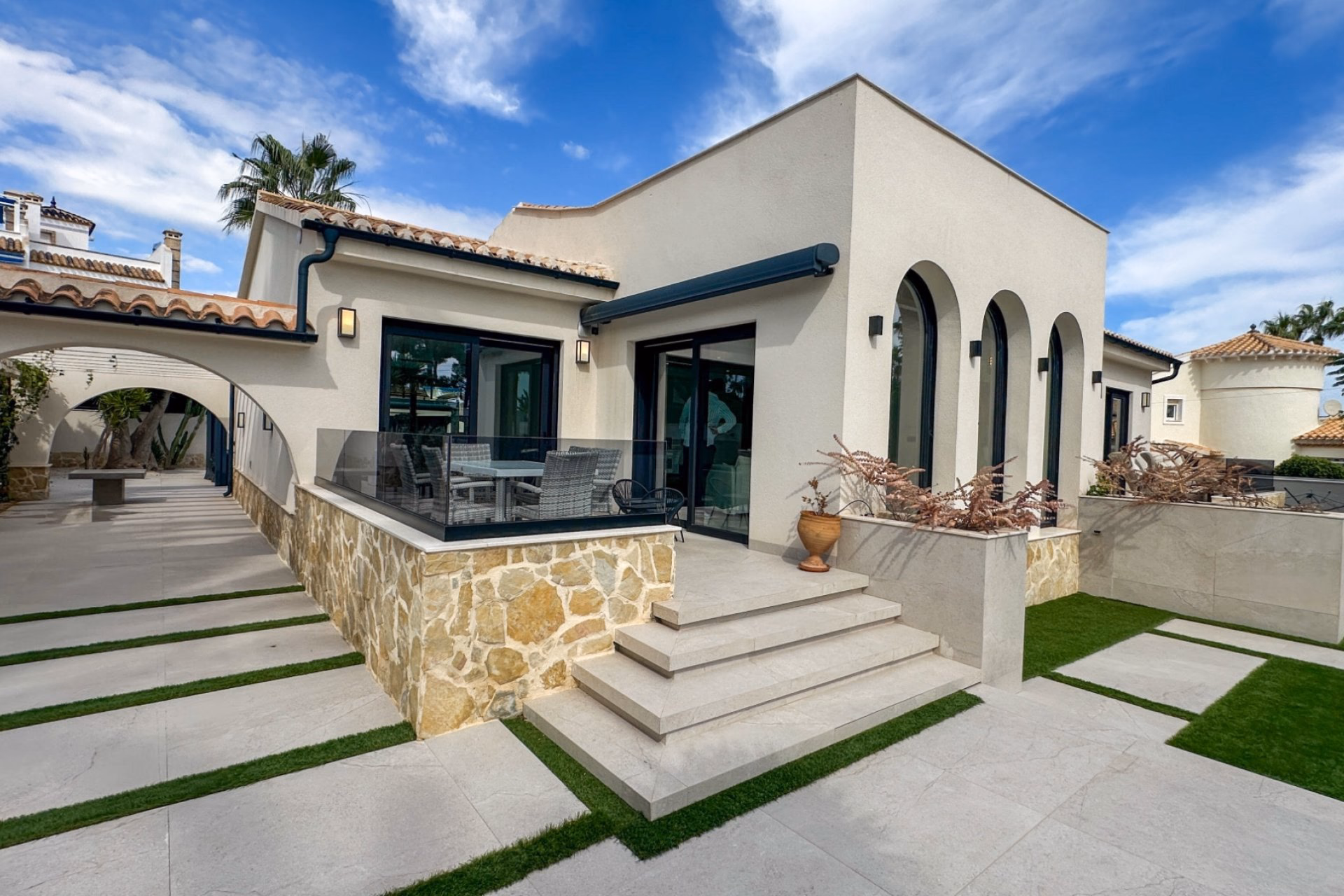 Villa exterior with arched doorway, stone base and steps to the garden