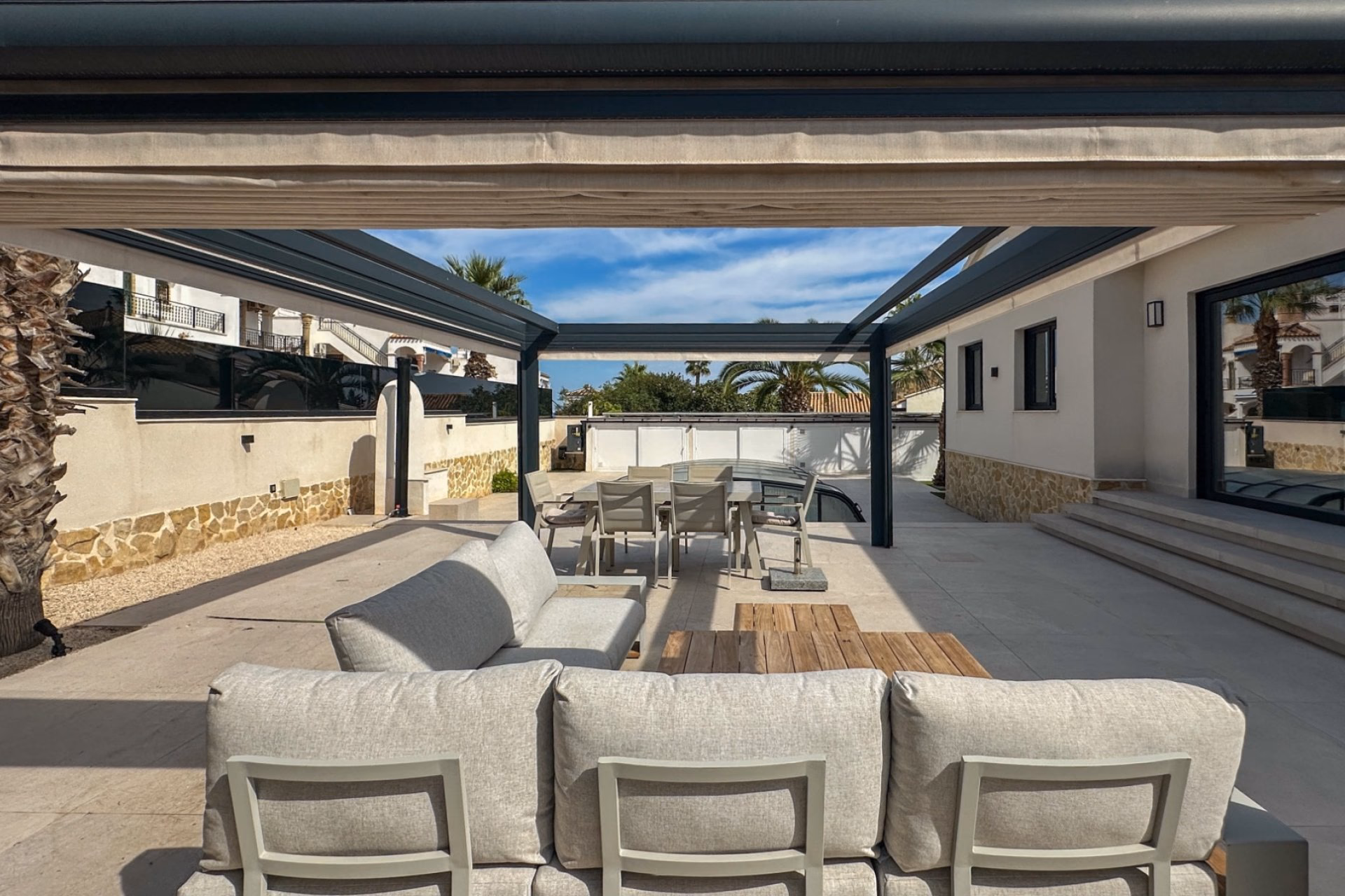 Terrace with outdoor sofas under an aluminium pergola beside the house