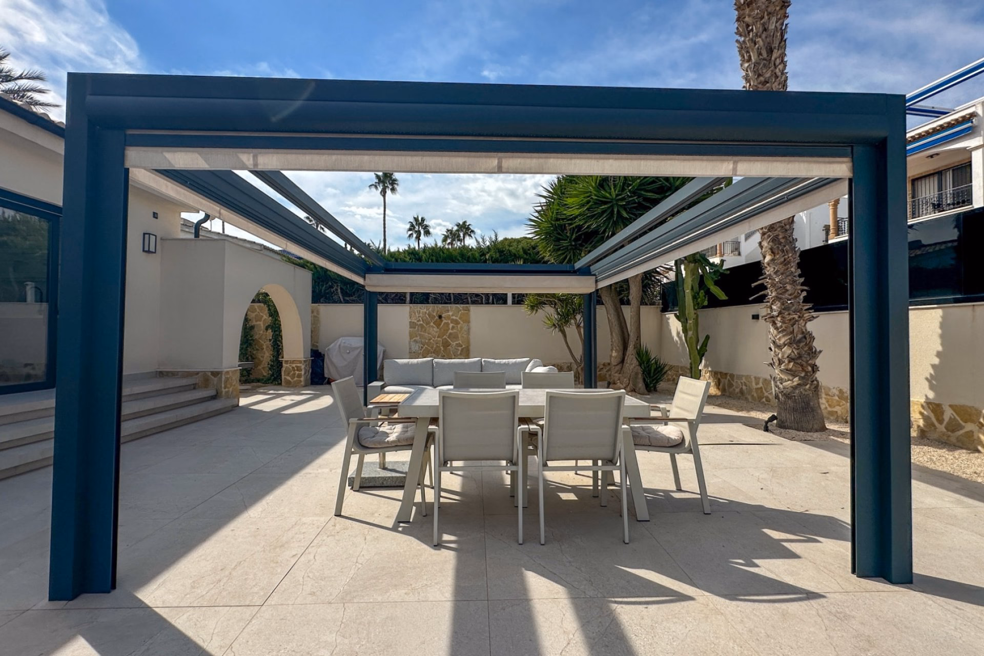 Large paved terrace with a pergola and outdoor furniture