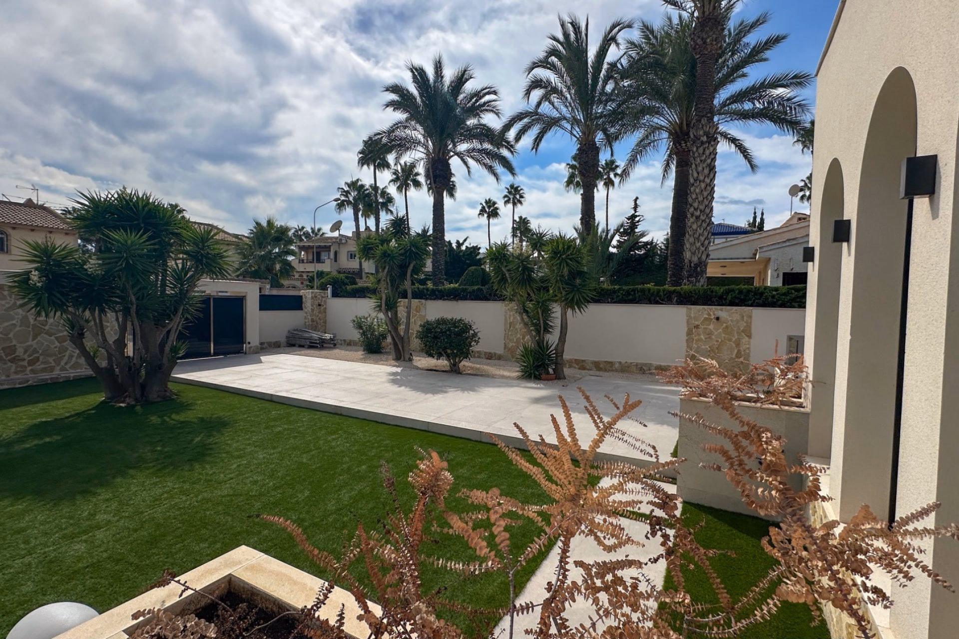 Lawned garden with palms and arched windows of the villa