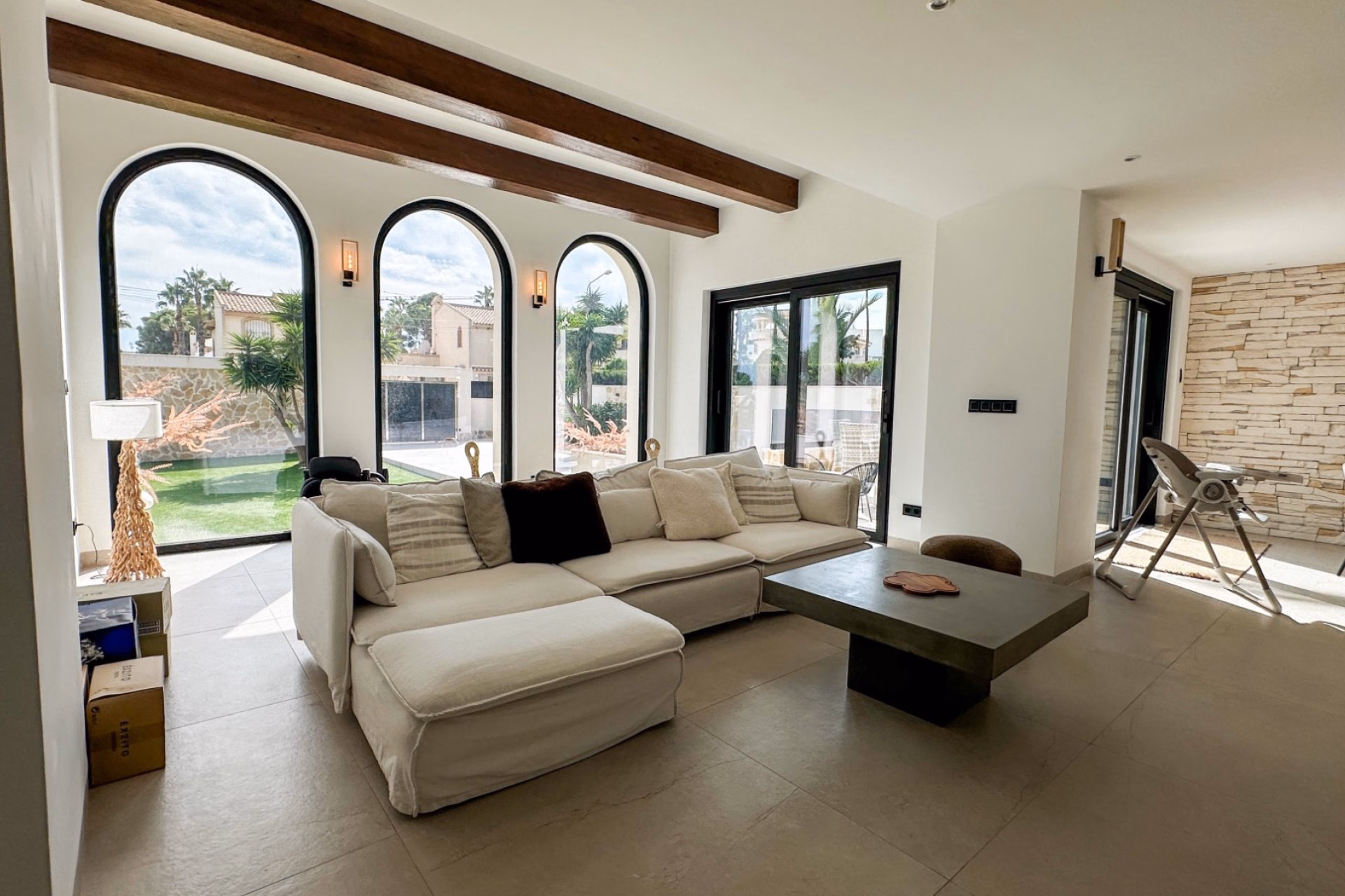 Open living area with sofa, coffee table and arched windows onto the garden