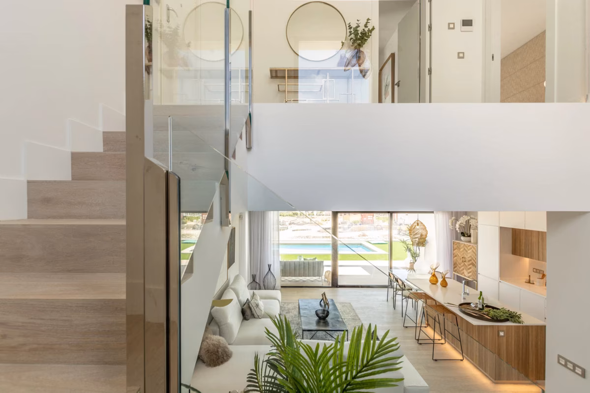 Staircase with a glass balustrade and a view down to the living room