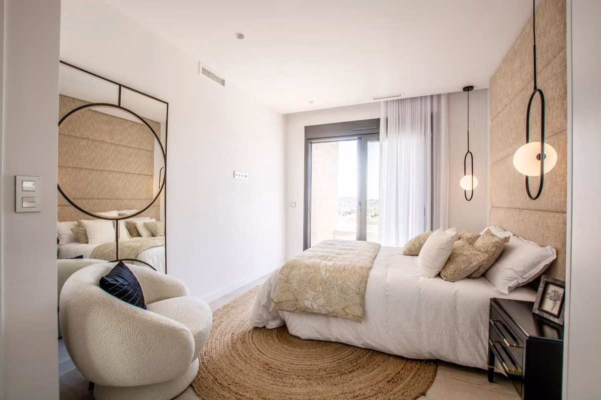 Bedroom with a round mirror and a view of the hills