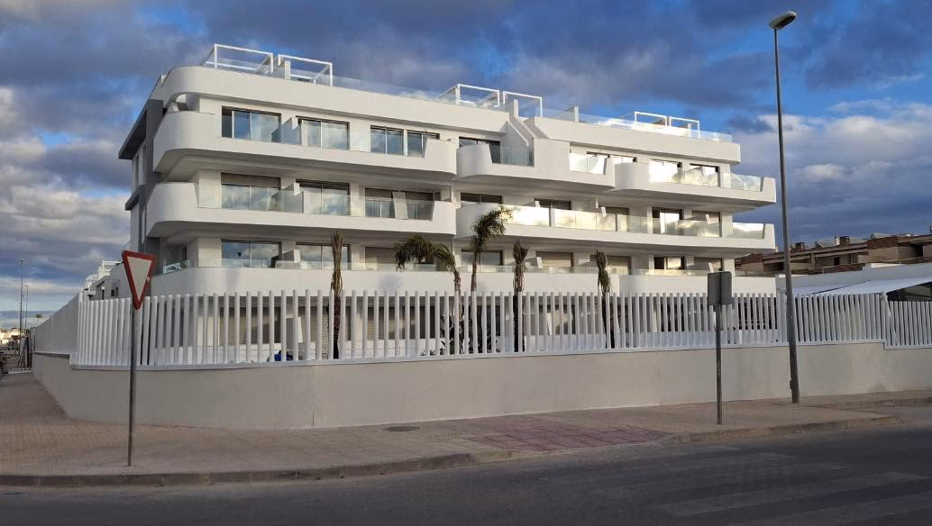 Edificio blanco de apartamentos con balcones visto desde la calle